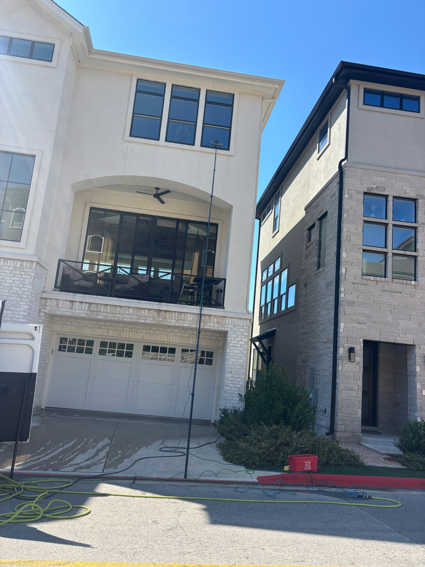 Clever’s cleaning the upstairs windows of a home with a long water-fed pole